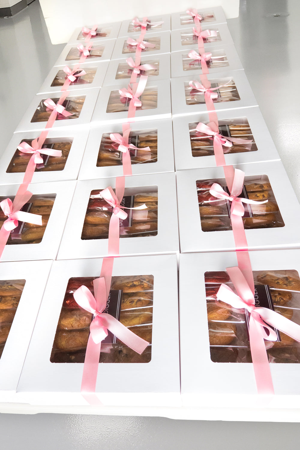 Rows of white Dough Digger gift boxes tied with pink ribbon, ready for a corporate order