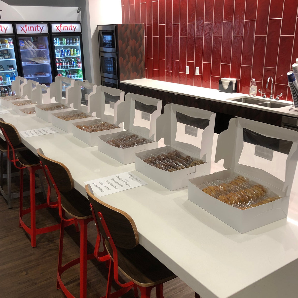 A row of open Dough Digger boxes set out along an office break-room counter, with a printed flavor card